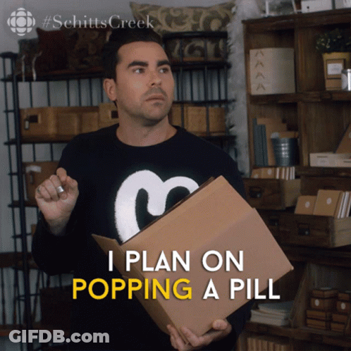 A Man In A Schitts Creek Sweater Holds A Cardboard Box GIF