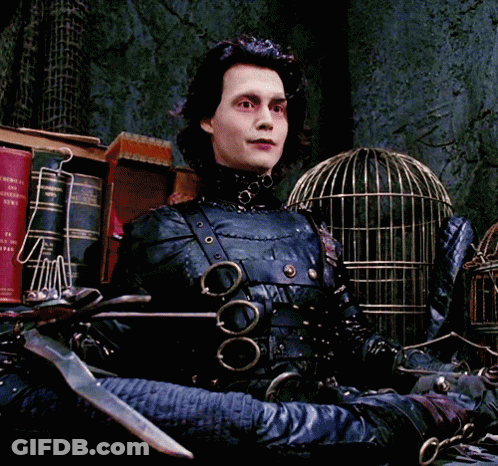 A Man In A Scissors Costume Is Sitting In Front Of A Cage GIF
