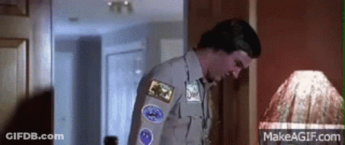 A Man In A Scout Uniform Is Standing In Front Of A Lamp In A Room . GIF