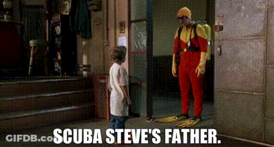 A Man In A Scuba Suit Is Standing Next To A Boy In A White Shirt And Talking To Him . GIF