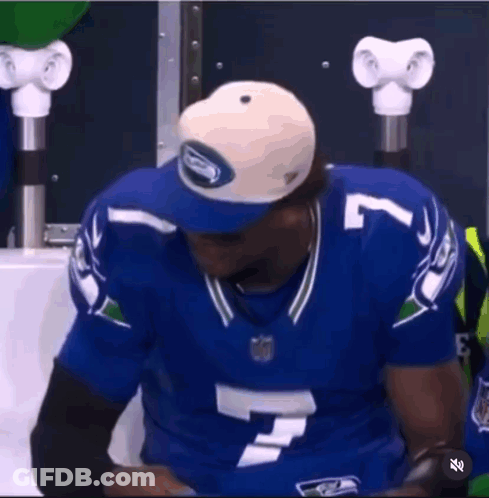A Man In A Seahawks Jersey Is Holding A Tablet . GIF