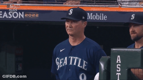 A Man In A Seattle Baseball Uniform Holds A Ticket In His Hand GIF