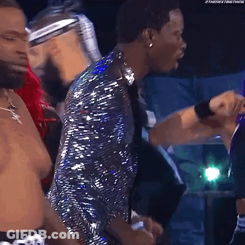 A Man In A Sequined Jacket Is Standing In Front Of A Group Of People . GIF