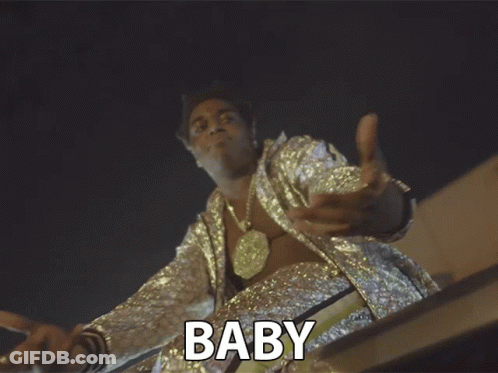 A Man In A Sequined Jacket With The Word Baby Above Him GIF