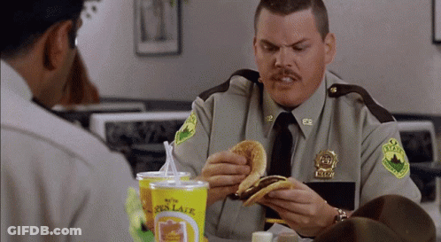 A Man In A Sheriff 'S Uniform Eating A Burger GIF