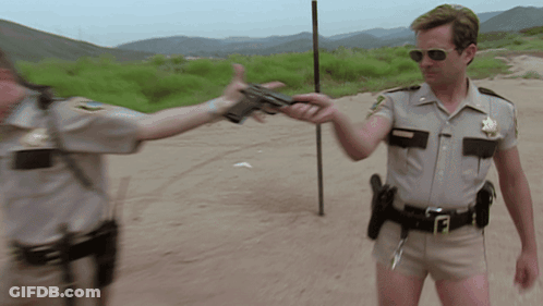 A Man In A Sheriff 'S Uniform Holds A Gun To Another Man GIF