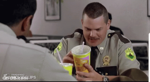 A Man In A Sheriff 'S Uniform Is Holding A Cup With A Straw And A Drink In It GIF
