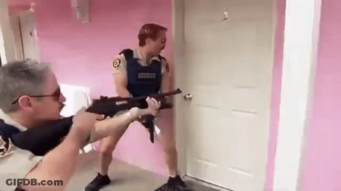 A Man In A Sheriff 'S Uniform Is Pointing A Gun At Another Man In A Room . GIF
