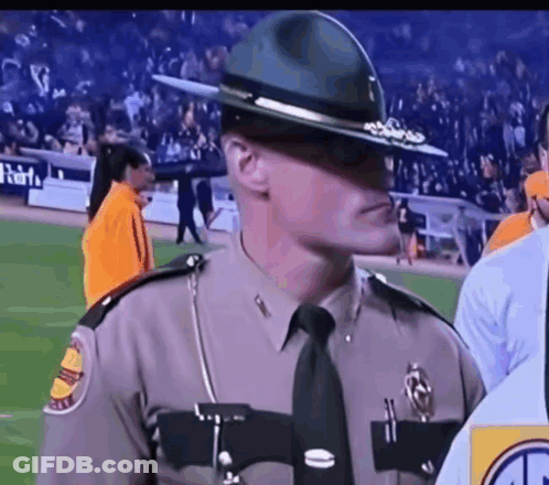 A Man In A Sheriff 'S Uniform Is Standing On A Football Field GIF