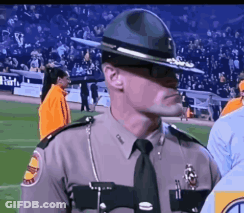 A Man In A Sheriff 'S Uniform Stands On A Stadium Field GIF