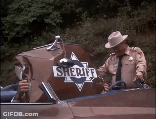 A Man In A Sheriff Uniform Is Standing Next To A Damaged Sheriff 'S Car GIF