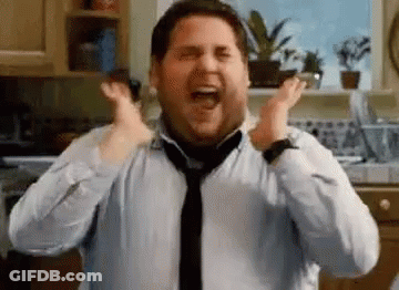 A Man In A Shirt And Tie Is Screaming With His Hands In The Air In A Kitchen . GIF