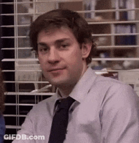 A Man In A Shirt And Tie Is Sitting In Front Of A Window In An Office . GIF