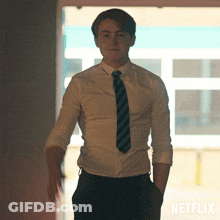 A Man In A Shirt And Tie Is Standing In Front Of A Netflix Sign GIF