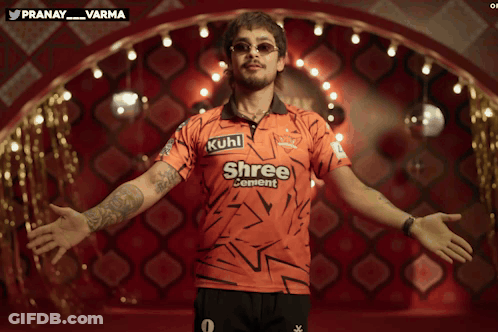 A Man In A Shree Cement Shirt Stands With His Arms Outstretched GIF