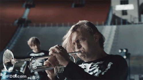 A Man In A Skeleton Shirt Plays A Trumpet In A Band GIF