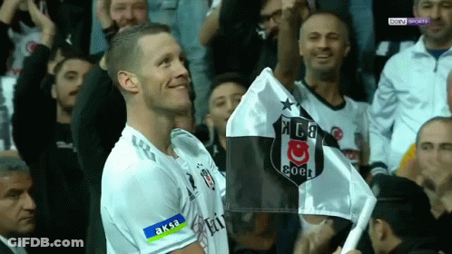 A Man In A Soccer Uniform Holds A Black And White Flag With The Letters Ksb On It GIF