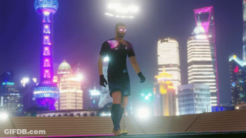 A Man In A Soccer Uniform Is Walking In Front Of A City Skyline At Night GIF