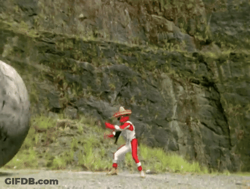 A Man In A Sombrero Is Standing Next To A Large Rock . GIF