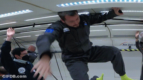 A Man In A Space Suit Is Being Lifted Up By Another Man In A Space Suit GIF