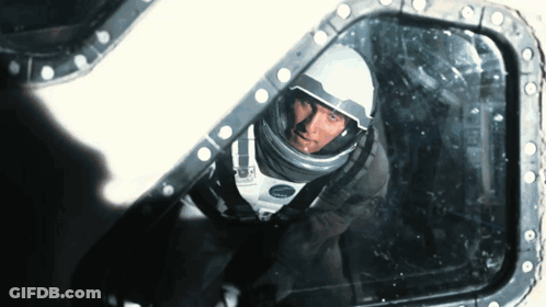 A Man In A Space Suit Is Looking Through A Window GIF