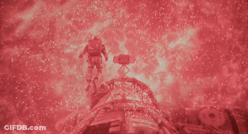 A Man In A Space Suit Is Surrounded By Red Sparkles GIF
