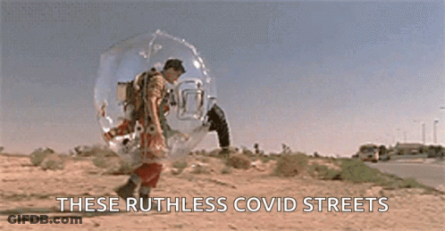 A Man In A Space Suit Is Walking Down A Road . GIF
