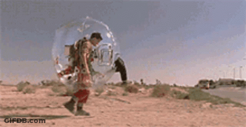 A Man In A Space Suit Is Walking Down A Road GIF