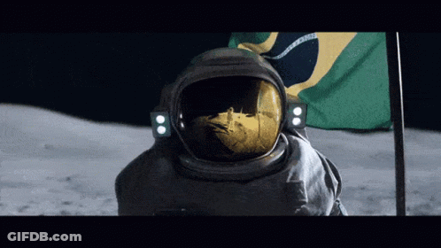A Man In A Space Suit Stands In Front Of A Brazilian Flag On The Moon GIF
