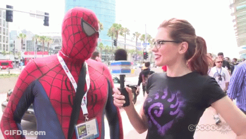 A Man In A Spider Man Costume Is Being Interviewed By A Woman GIF