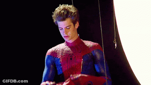 A Man In A Spider-Man Costume Is Standing In Front Of A White Light . GIF