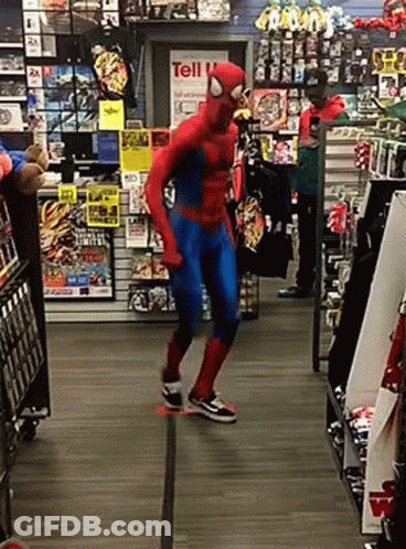A Man In A Spiderman Costume Is Dancing In Front Of A Sign That Says Tell GIF