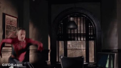 A Man In A Spiderman Costume Is Jumping In Front Of A Poster That Says Wanted GIF