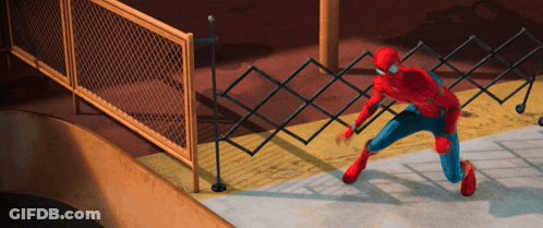 A Man In A Spiderman Costume Is Kneeling Down In Front Of A Chain Link Fence GIF