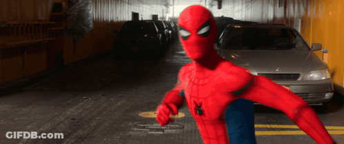 A Man In A Spiderman Costume Is Standing In A Parking Lot GIF