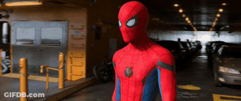 A Man In A Spiderman Costume Is Standing In A Parking Lot GIF