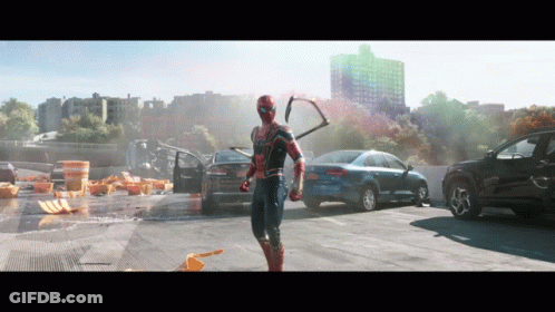 A Man In A Spiderman Costume Is Standing In A Parking Lot With Cars GIF