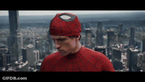 A Man In A Spiderman Costume Is Standing In Front Of A City GIF