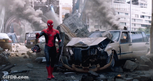 A Man In A Spiderman Costume Is Standing In Front Of A Destroyed City GIF