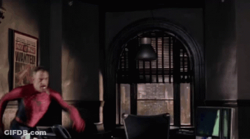 A Man In A Spiderman Costume Is Standing In Front Of A Poster That Says Wanted GIF