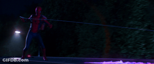A Man In A Spiderman Costume Is Standing In Front Of A Street Light At Night GIF