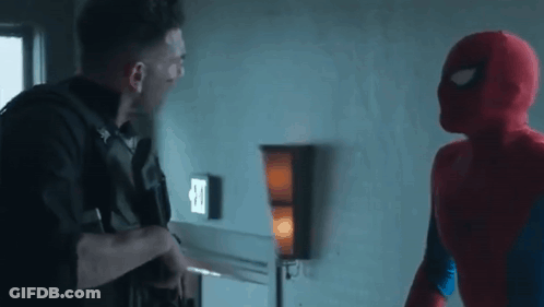 A Man In A Spiderman Costume Is Standing Next To A Man In A Punisher Costume In A Room . GIF