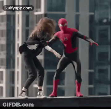 A Man In A Spiderman Costume Is Standing Next To A Woman On A Ledge . GIF
