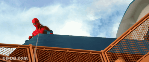 A Man In A Spiderman Costume Is Standing On Top Of A Fence GIF