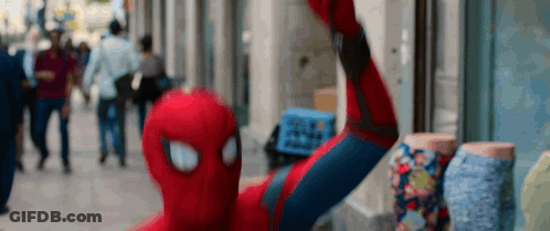 A Man In A Spiderman Costume Is Taking A Selfie On A City Street GIF
