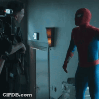A Man In A Spiderman Costume Is Talking To Another Man GIF