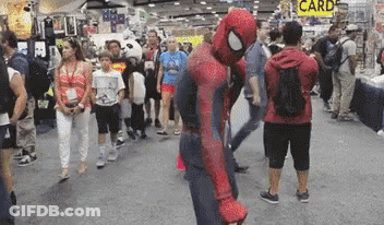 A Man In A Spiderman Costume Stands In A Crowd Of People GIF