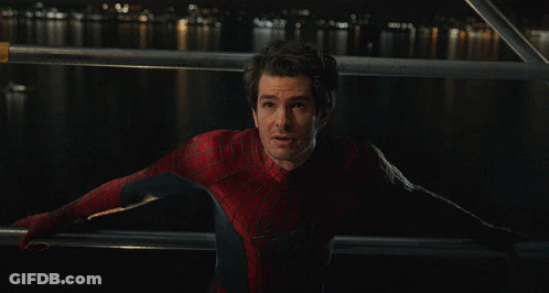 A Man In A Spiderman Costume Stands In Front Of A Body Of Water At Night GIF