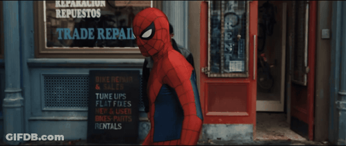 A Man In A Spiderman Costume Stands In Front Of A Sign That Says Reparacion Repuestos Trade R. GIF