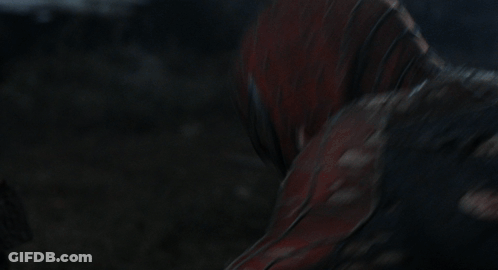 A Man In A Spiderman Suit Is Holding A Spider Web In His Hand GIF